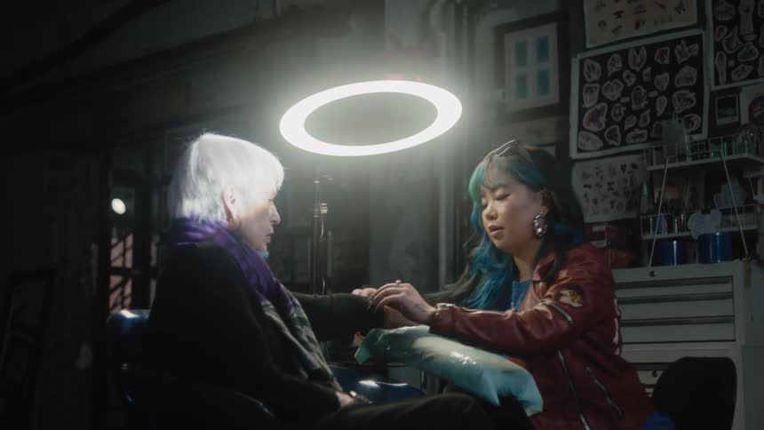 A tattoo artist moves the jewelry and sleeve on the arm of a customer in preparation for a tattoo