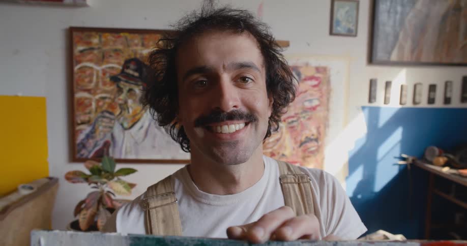 A man smiles while holding a painting