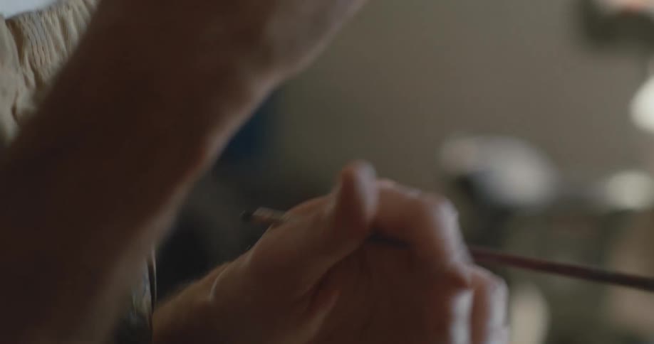 An artist talks and moves his hands and then paints on a canvas