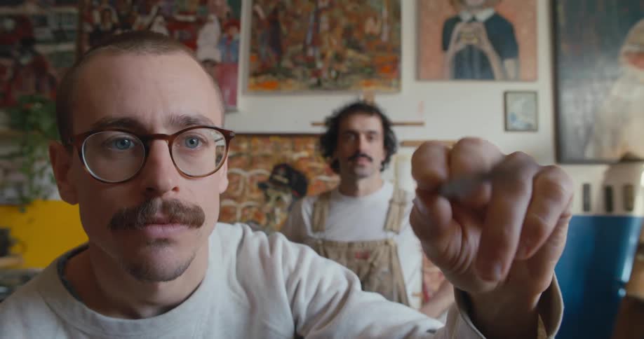 Close up of the face of an artist painting with a brush inside a studio