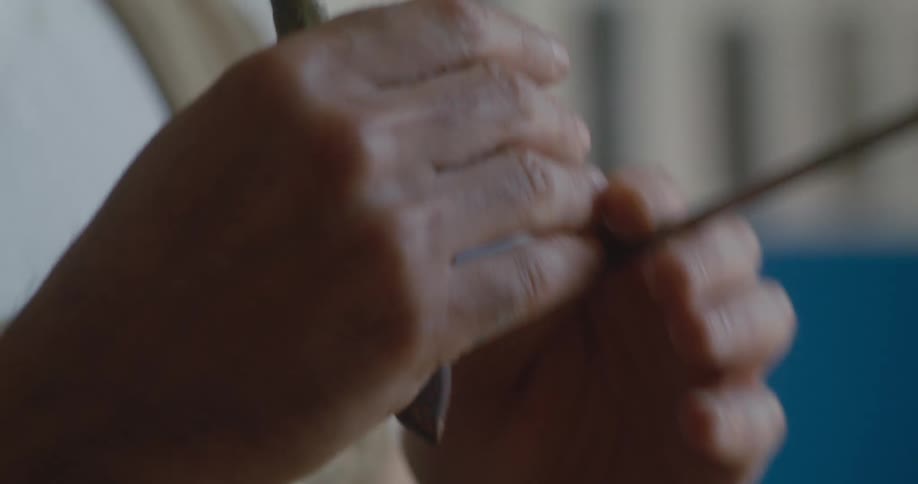 A painter holding a paintbrush moves his hands in the air