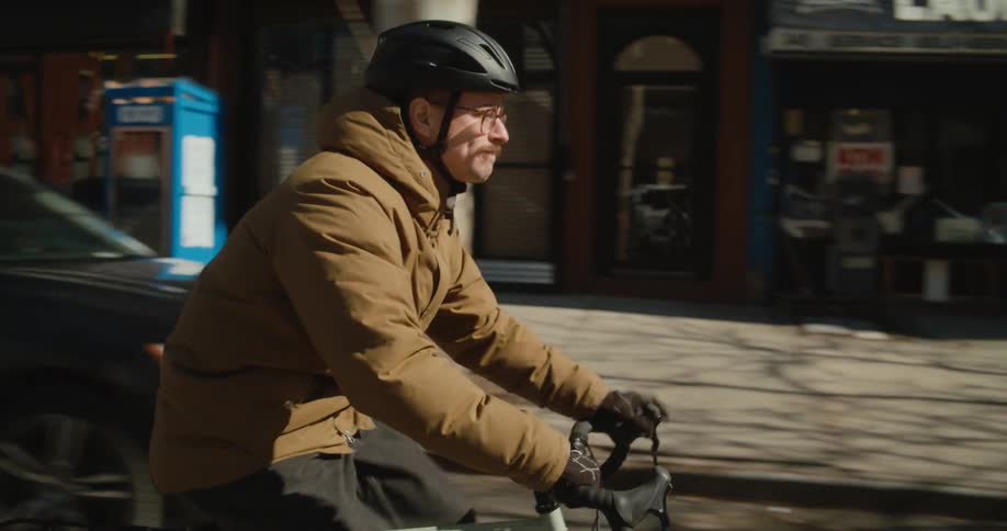 A man biking down a city street passes teenagers in a crosswalk