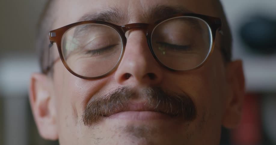 Man with mustache wearing eyeglasses smiles