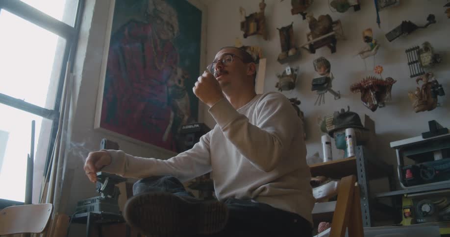 A man is smoking and sitting on a chair indoors