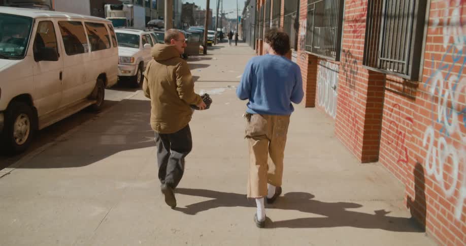 Two men are walking together through a downtown city using sign language to communicate