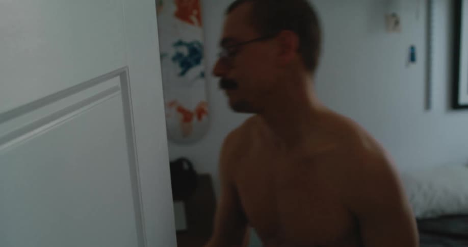 Man laying in bed texting on the phone stands up and starts dressing