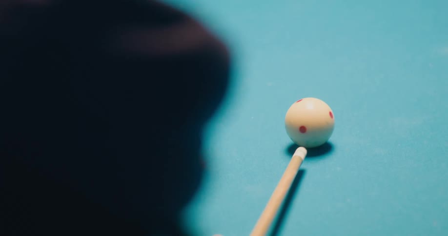 A person hits a white and red pool ball