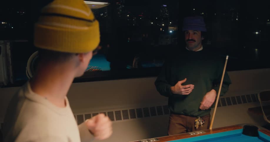 Two men are standing near a pool table talking in sign language