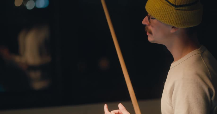 A man is holding a pool cue and talking with sign language