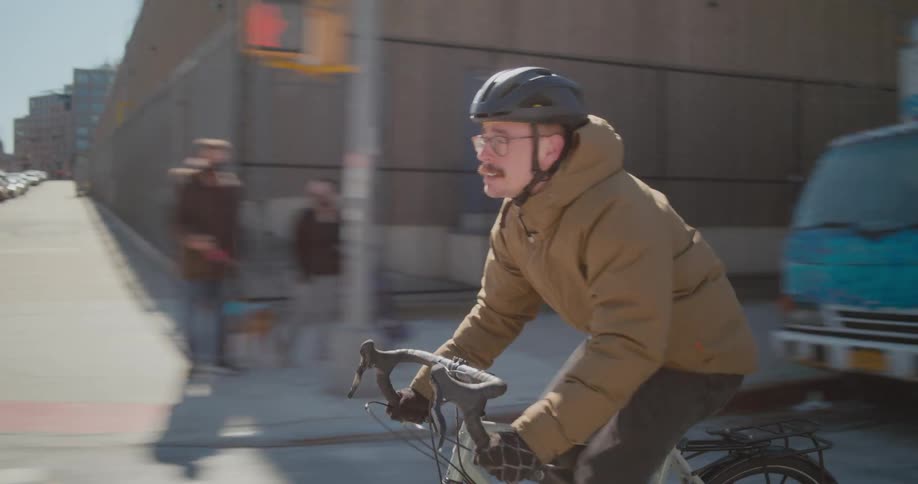 A man is biking through a downtown city at midday