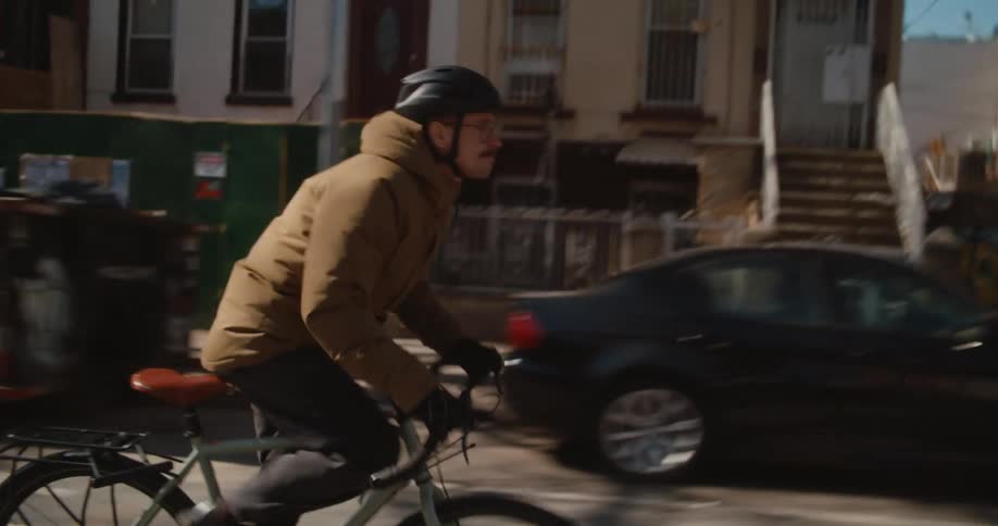 Young man with a mustache wearing a helmet rides a bicycle on the city streets