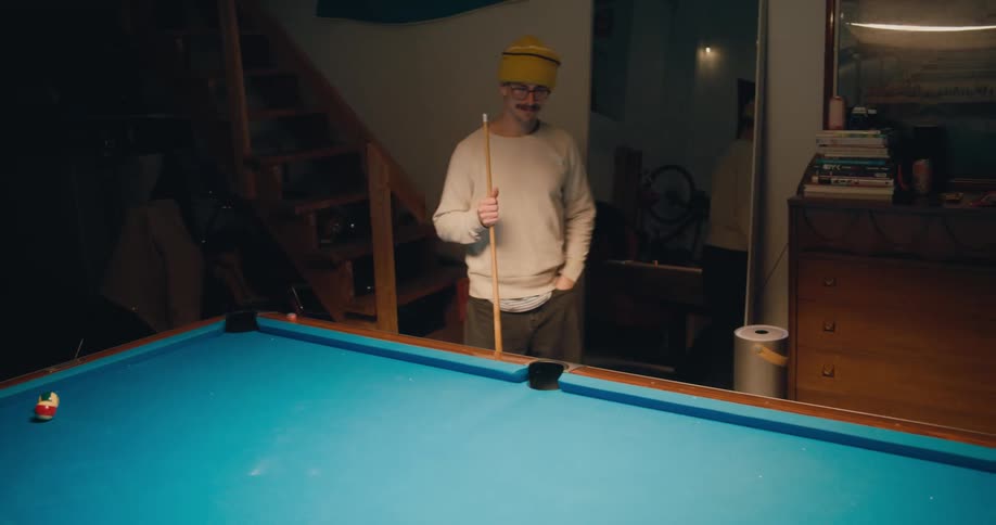 A man is playing a game of pool indoors