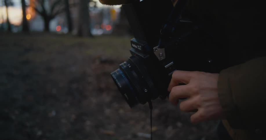 A man takes photos outside as cars drive past in the distance