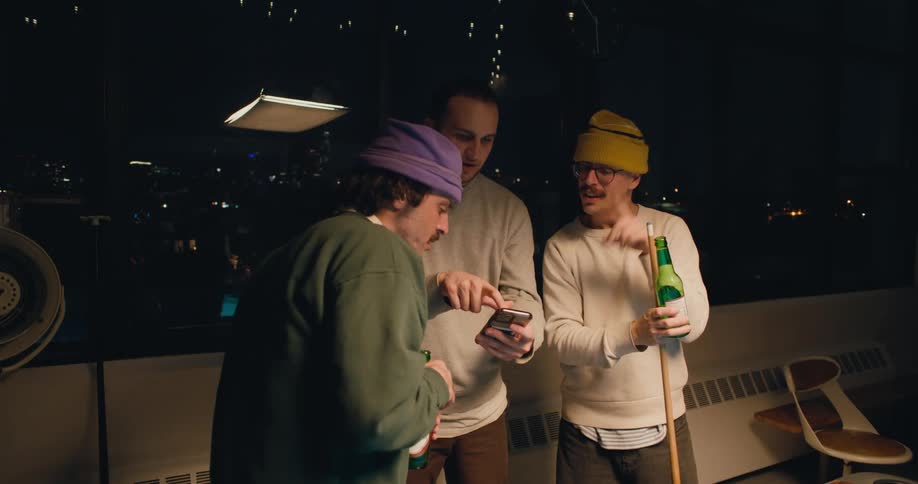 Three friends are talking on a balcony together at night