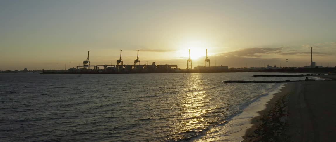 Birds fly over the water near a shipping port