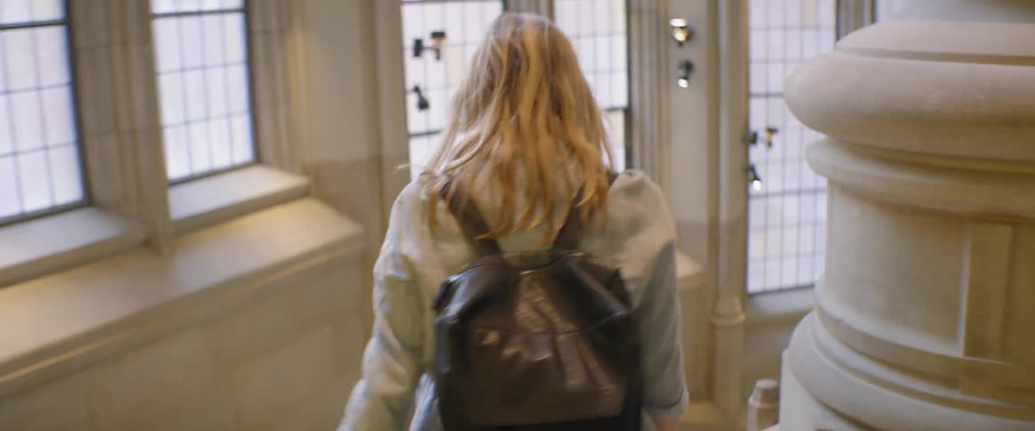 A woman walks down stone steps in a building