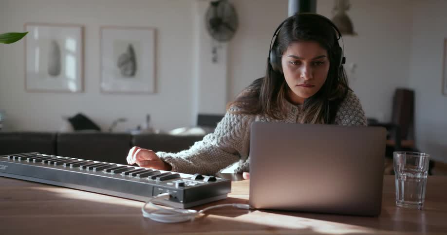 A woman is listening to music while looking at a laptop