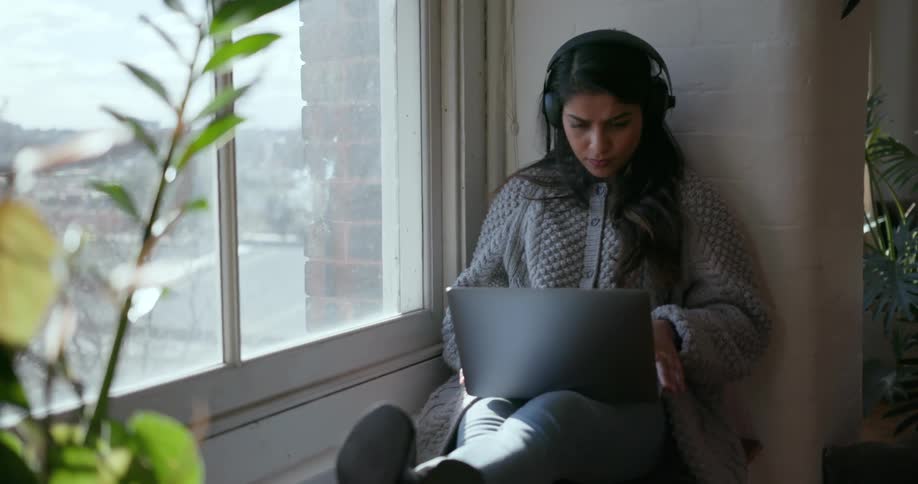 A girl sits on the windowsill listening to music