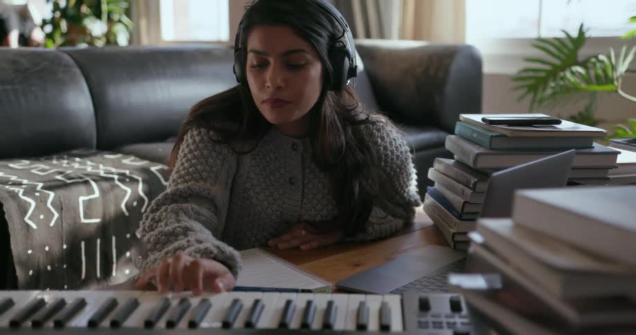 Girl sits at a coffee table with a keyboard and writes
