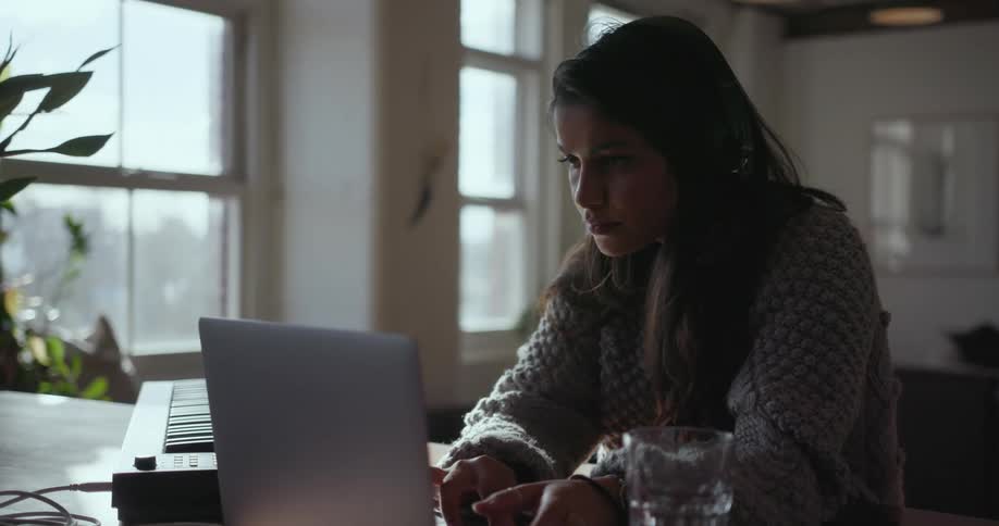 A girl uses a laptop by a keyboard