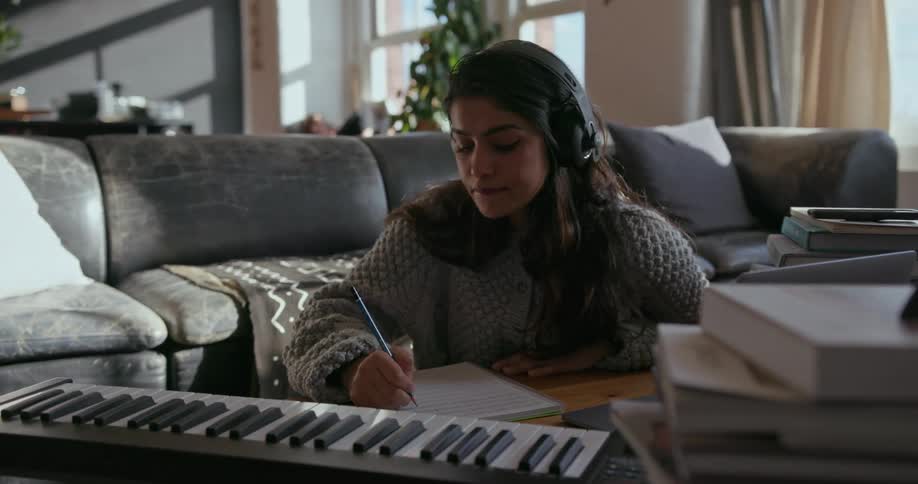 Girl sits at a coffee table with a keyboard and writes