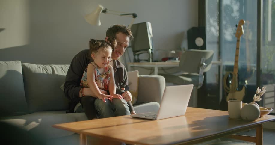 A father and daughter talking to someone on a laptop