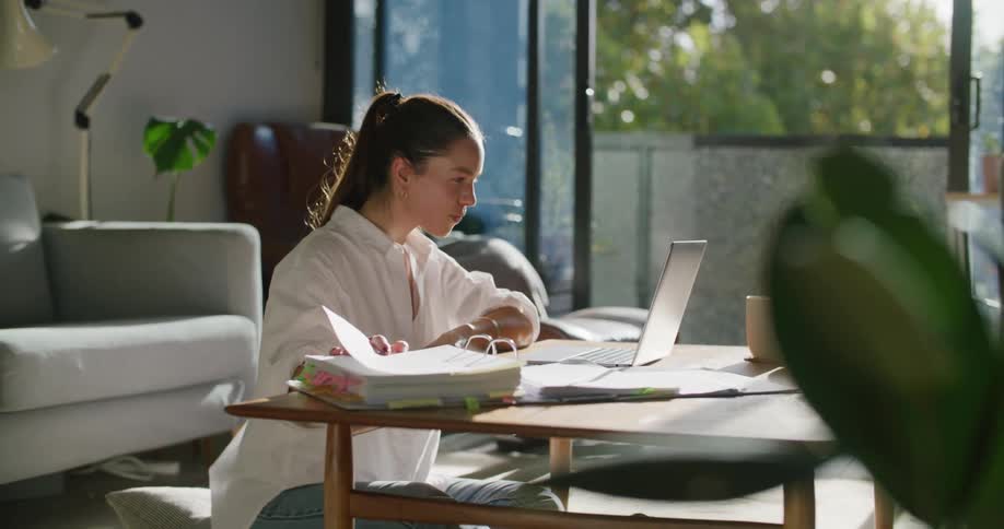Woman sits on floor in living room conversing via laptop