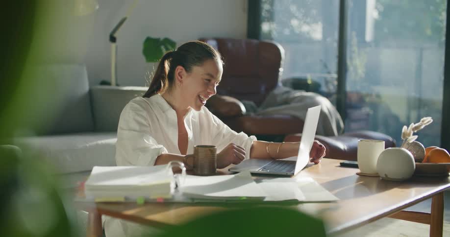 A woman typing on a laptop and laughing