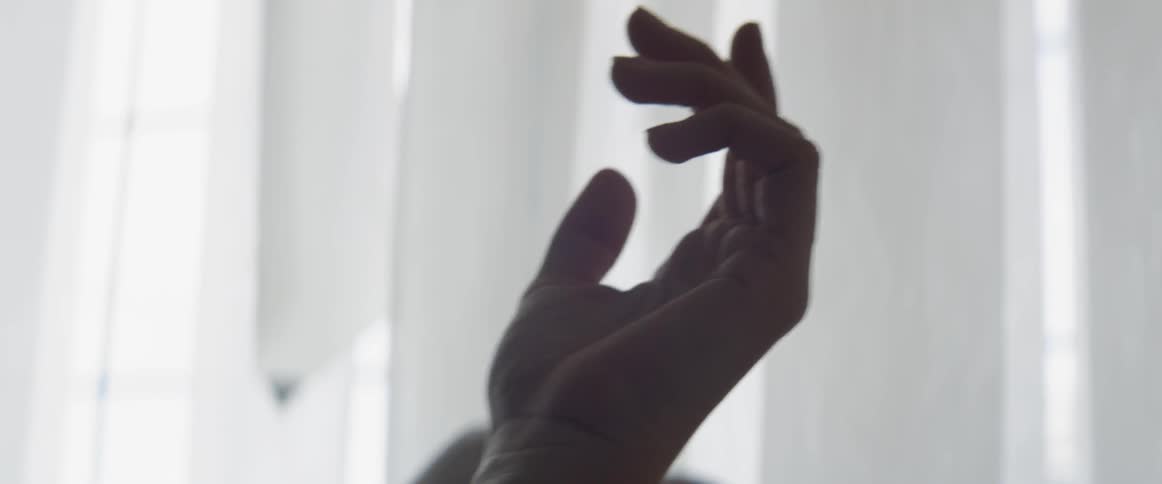 Two hands rub together in front of a window blind