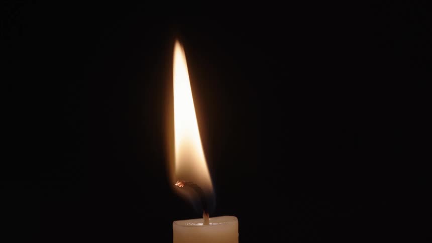 The flaming wick of a candle against black