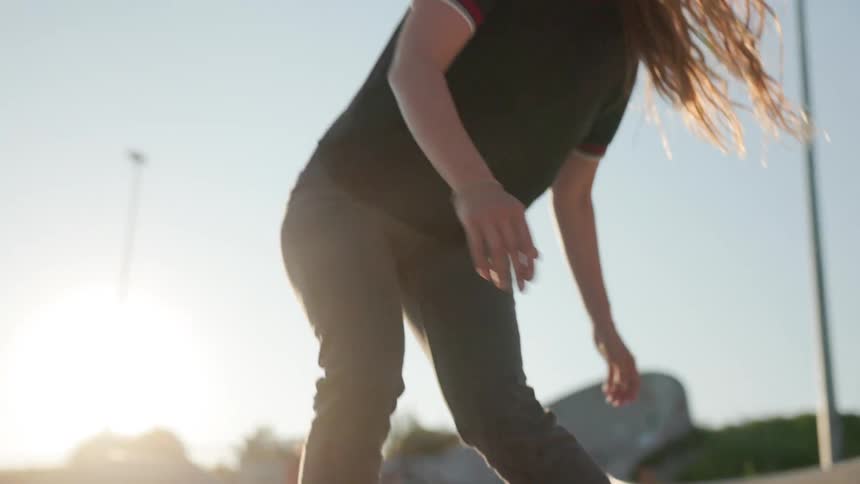 A woman skateboards through a skate park during the day