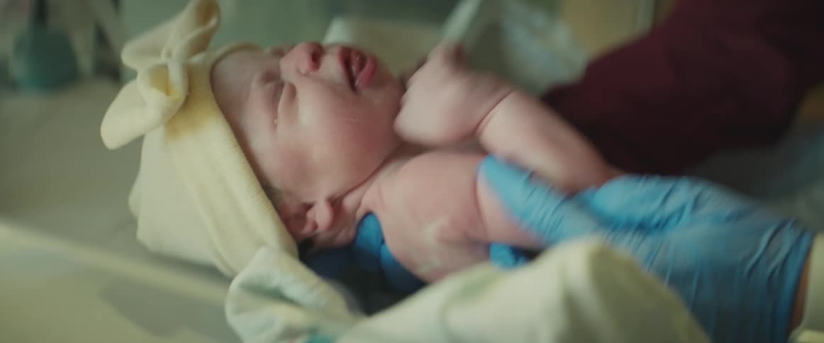 A nurse picks up a newborn baby girl