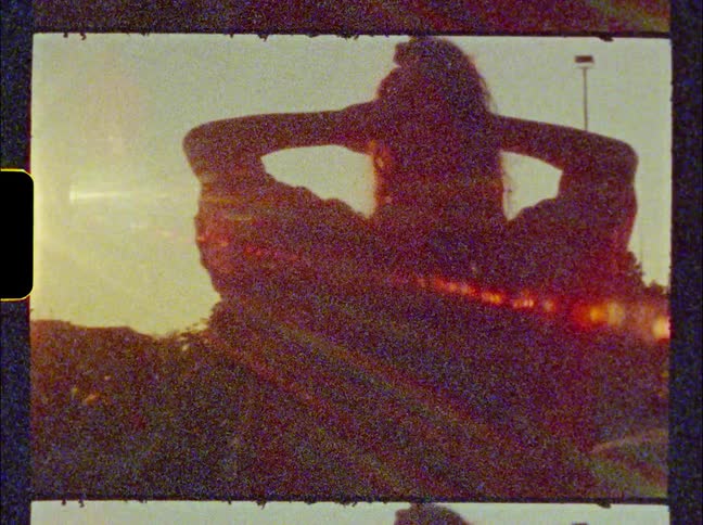 Woman stands with her hands shading her eyes as she looks toward the sky while kids run by