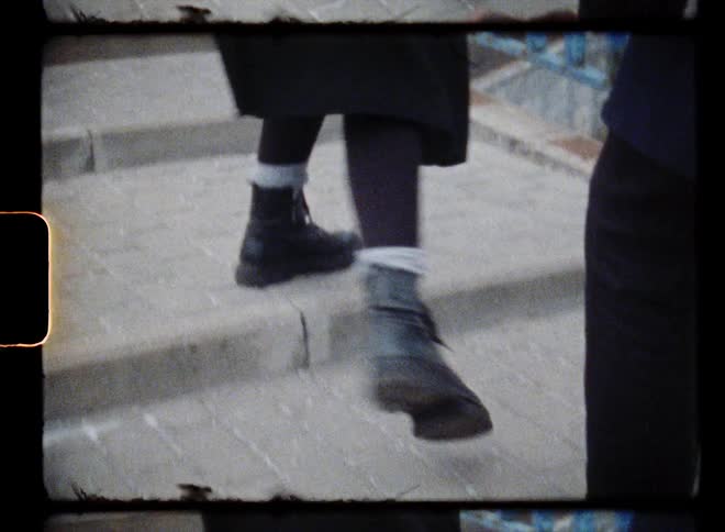 A pair of people walk together up a cement staircase outdoors during the day