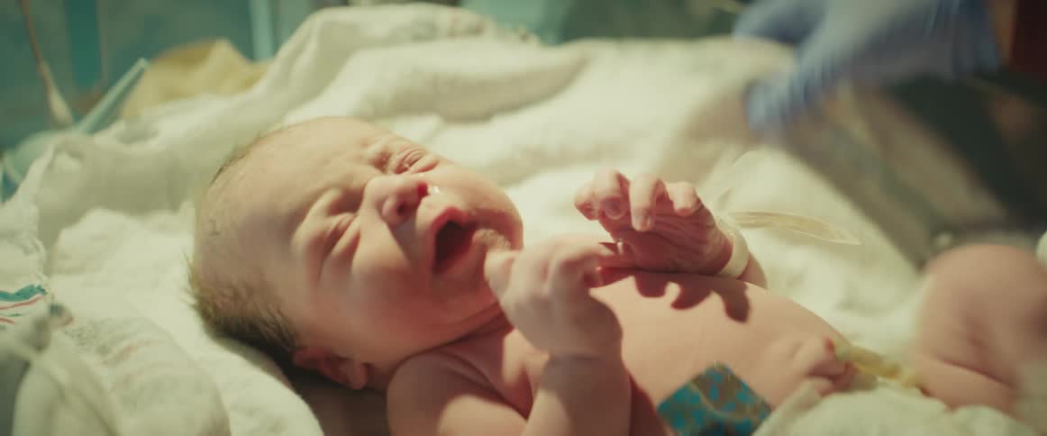 A nurse hurries to swaddle a newborn baby in the hospital