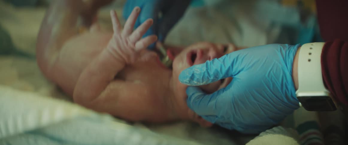 A newborn stops crying as a nurse listens to his heart