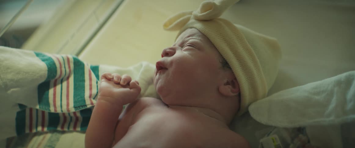 Baby with yellow hat lies in baby incubator