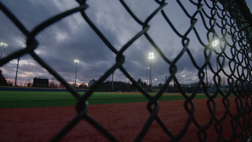 A green grass sports field with players gathered on the opposite side