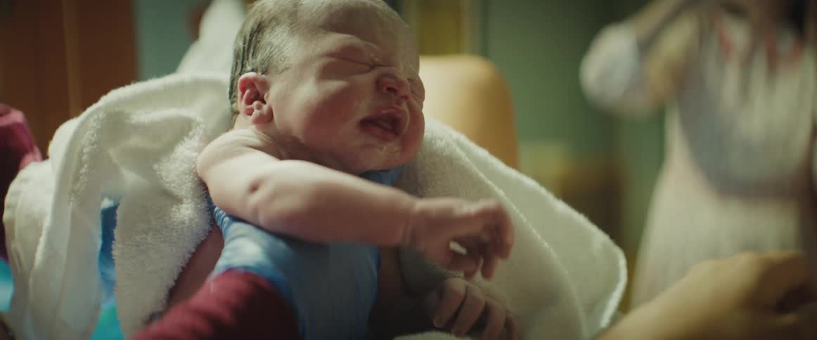 People take photos as a mother holds her newborn baby in the hospital