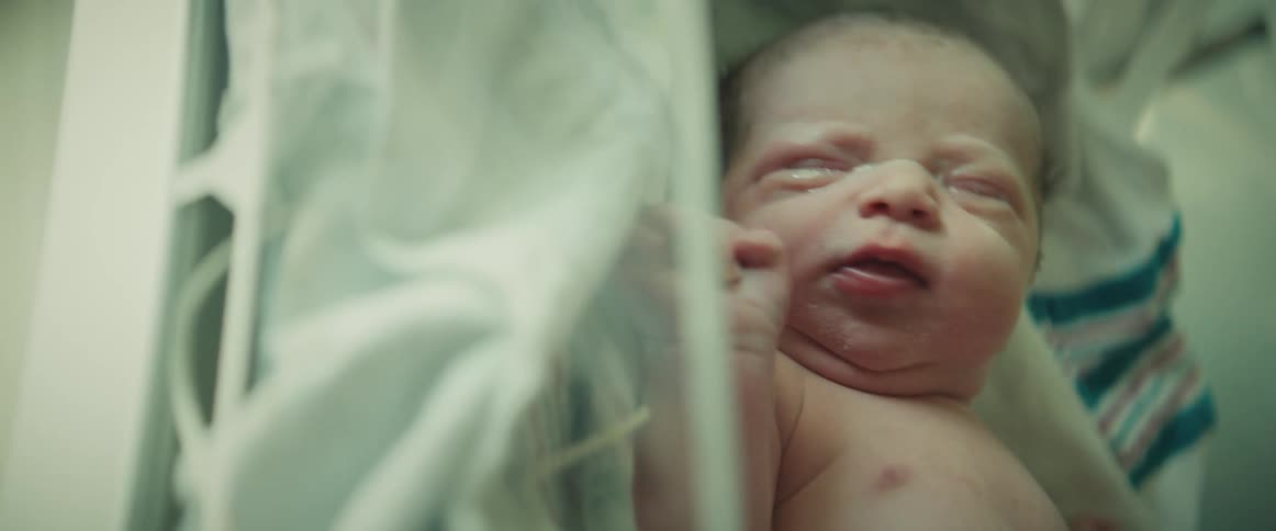 Newborn baby lies in incubator crying in hospital