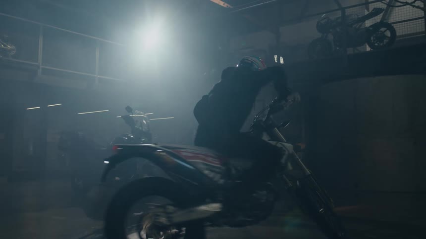 A man is driving in circles with a motorcycle indoors