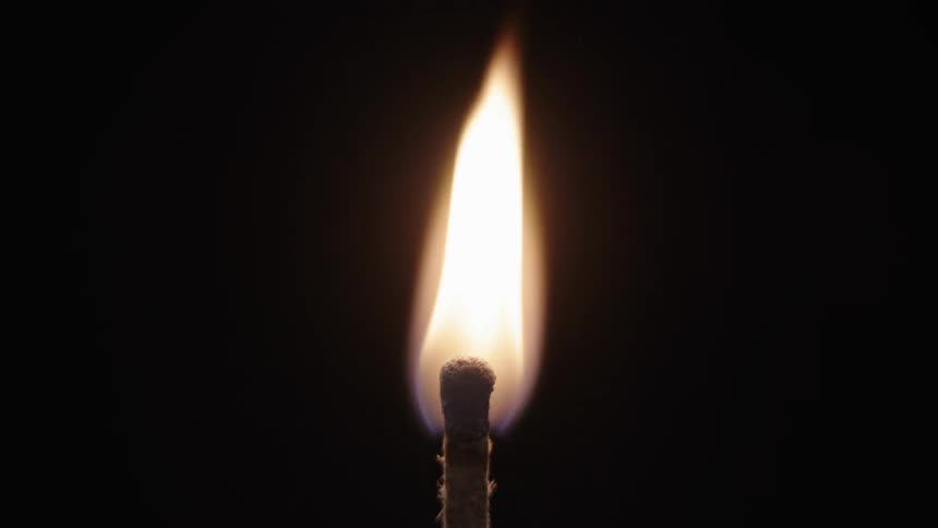 A hand lighting a match stick with a lighter on a black background