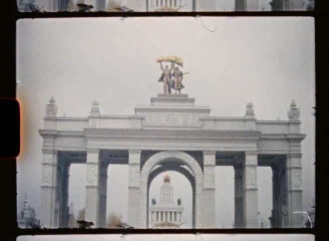 Tourists visit a monument with an arch and columns with a sculpture on top
