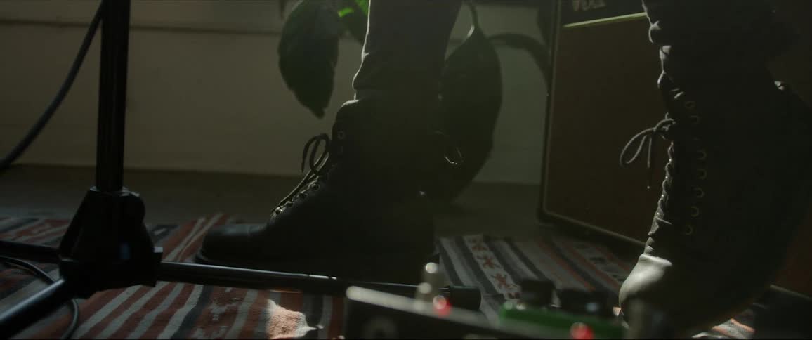 Boots of a musician standing near a microphone stand at home beating a foot