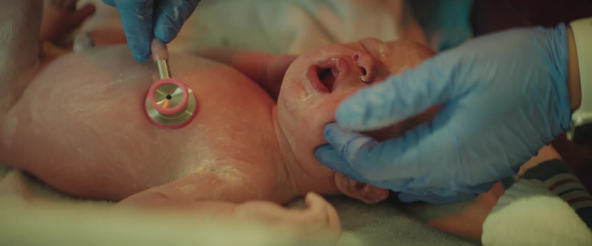Nurse examines baby with stethoscope in hospital nursery