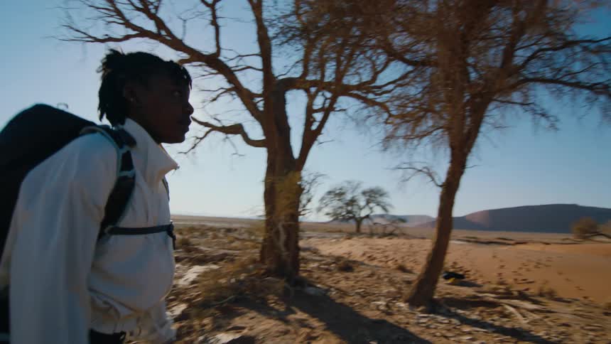 Young woman carrying a backpack walking on the desert near the sand dunes
