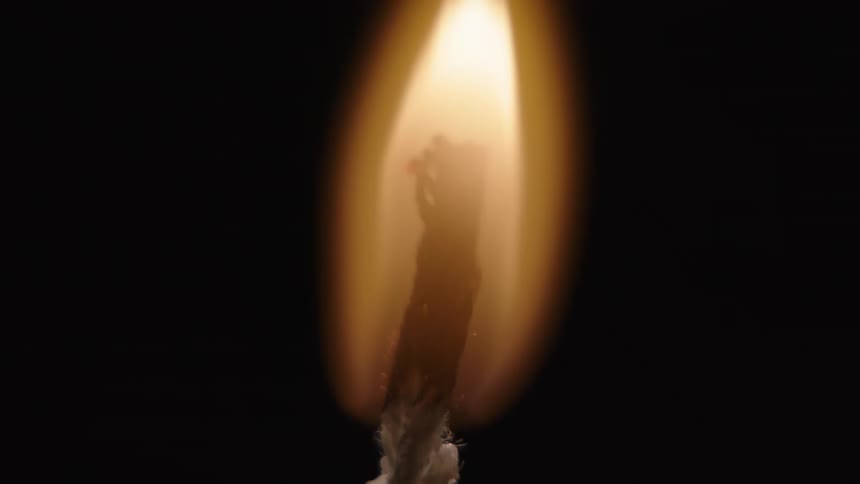 A person lights a candle in a dark room