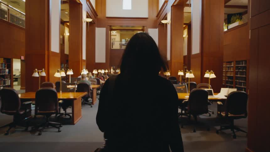 A woman carries a messenger bag into the library