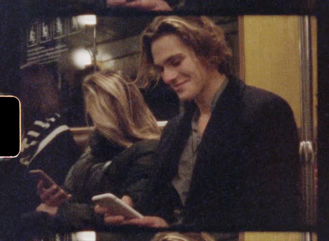 Three people are looking at their cellphones while riding a train