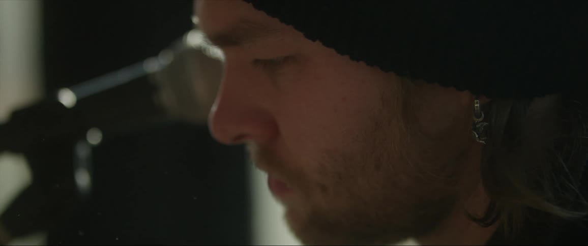 A man sits in a room next to a microphone